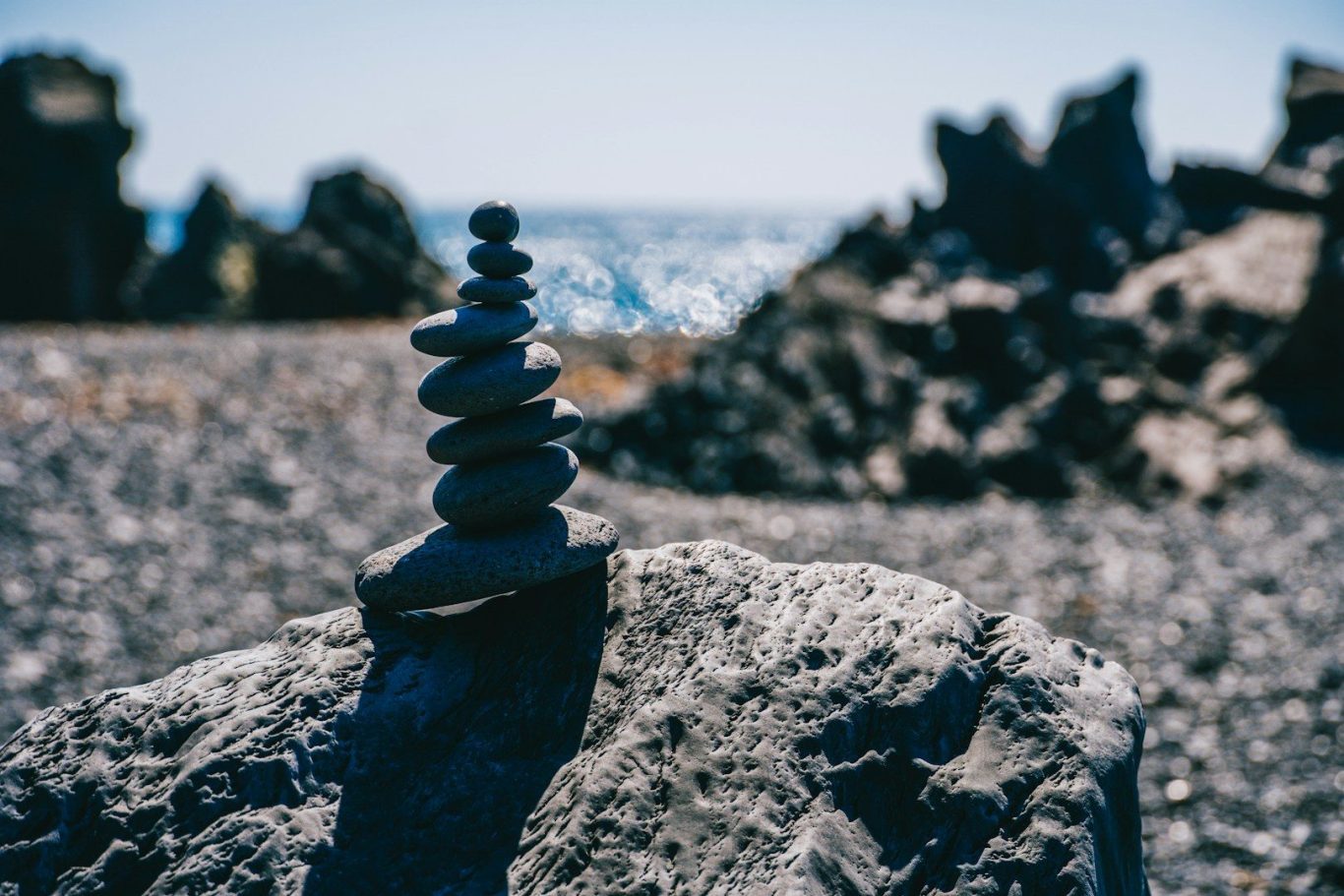 A rocky shore, with several rocks stacked in a neat, stable column in the foreground